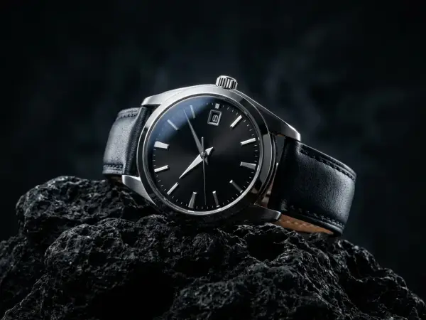Armbanduhr auf schwarzem Gestein mit hartem Gegenlicht